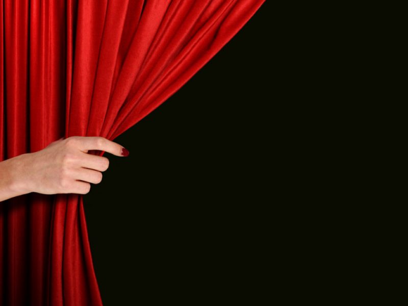 Women hand opening red curtain over black background